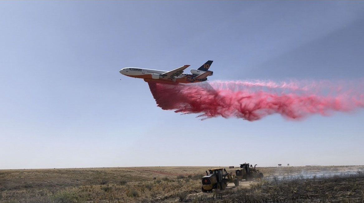 DC-10 airplane drops red retardant ahead of heavy equipment building fireline on the Helium Fire in Moore County